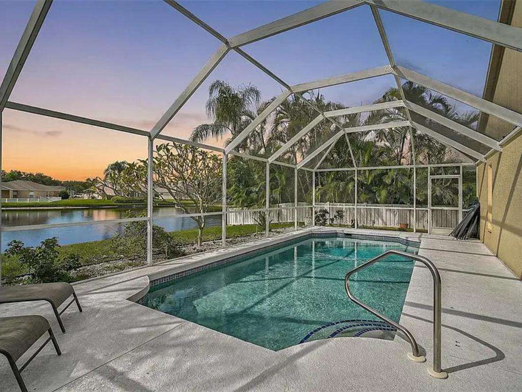 Serene screened pool patio with tranquil water views at sunset - property