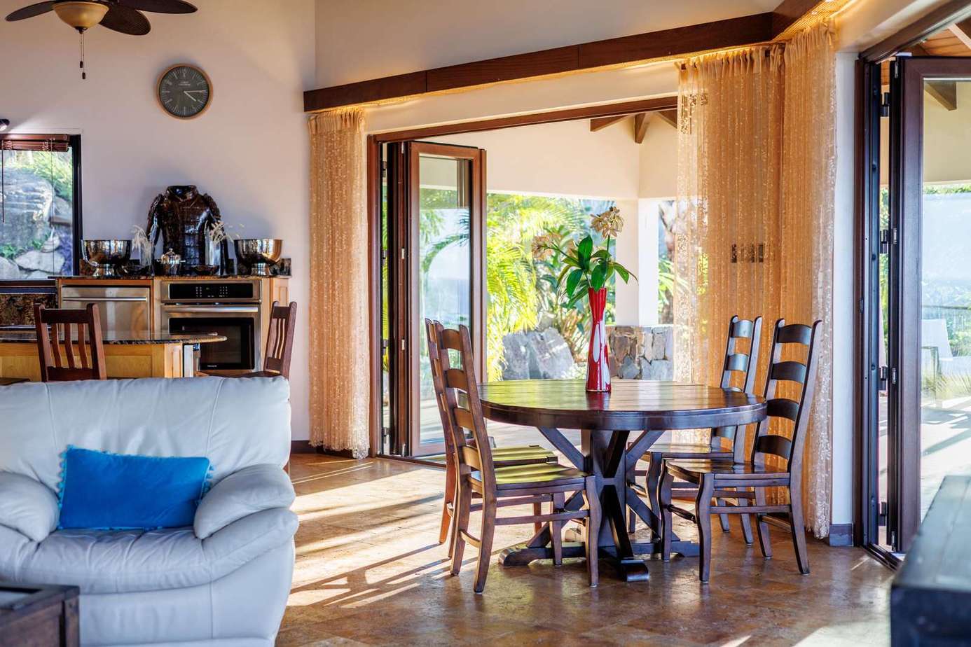 Sunlit dining area with open doors to lush views