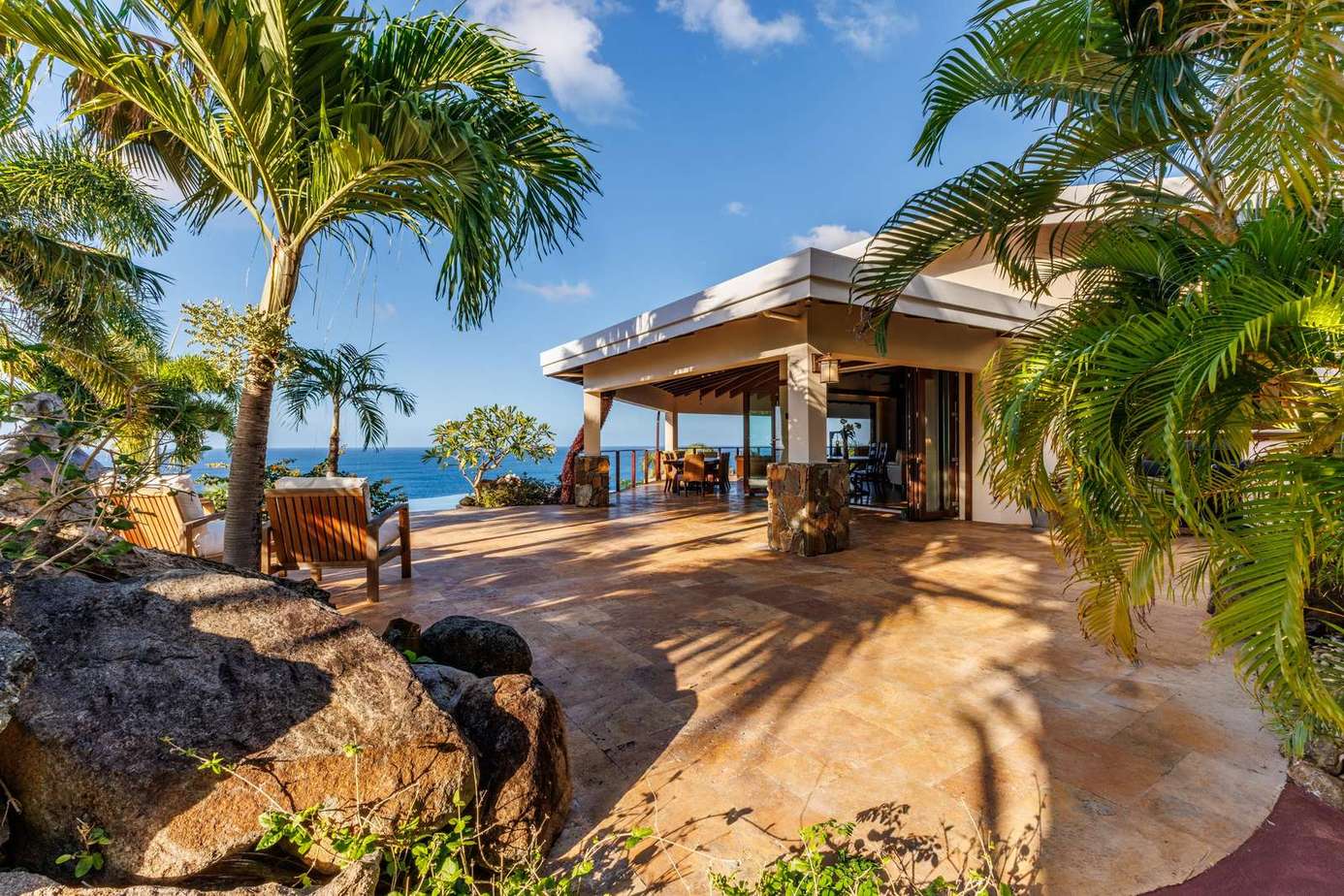 Ocean-view patio with lush tropical landscaping and cozy seating