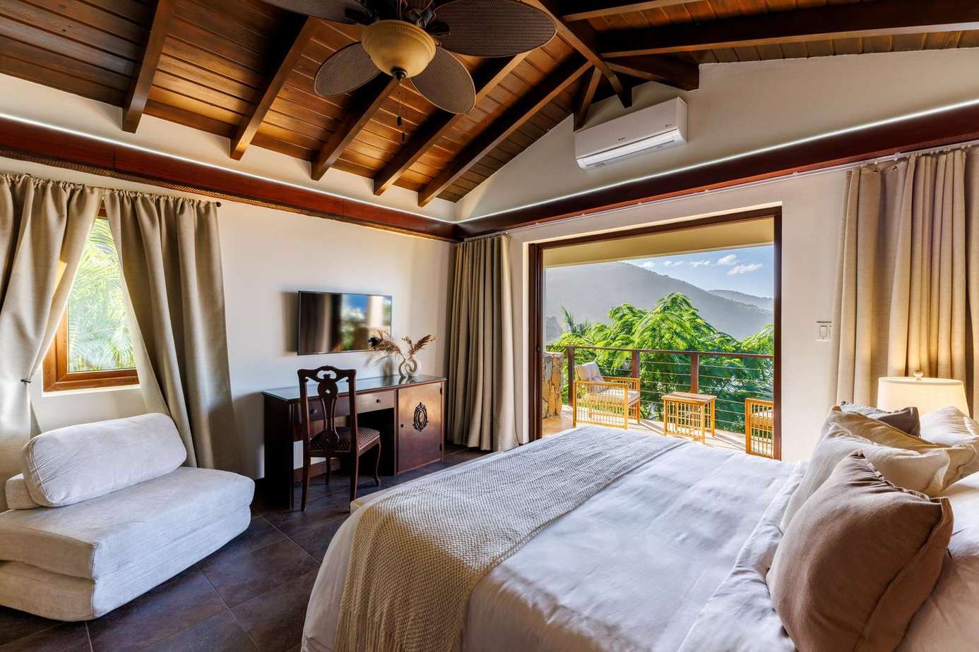 Cozy bedroom with vaulted ceilings and scenic balcony views