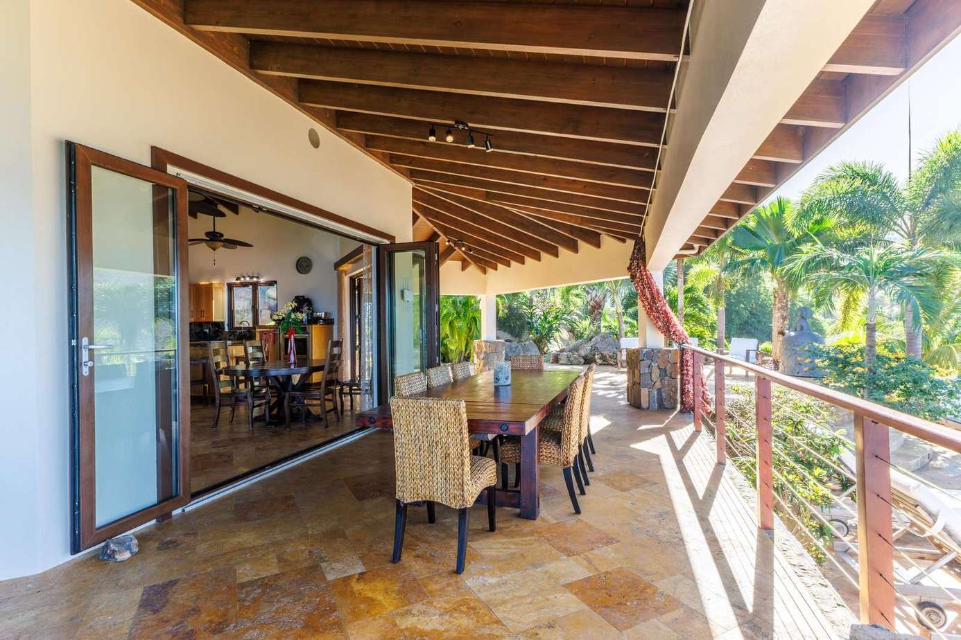 Spacious covered patio with tropical garden views and dining area