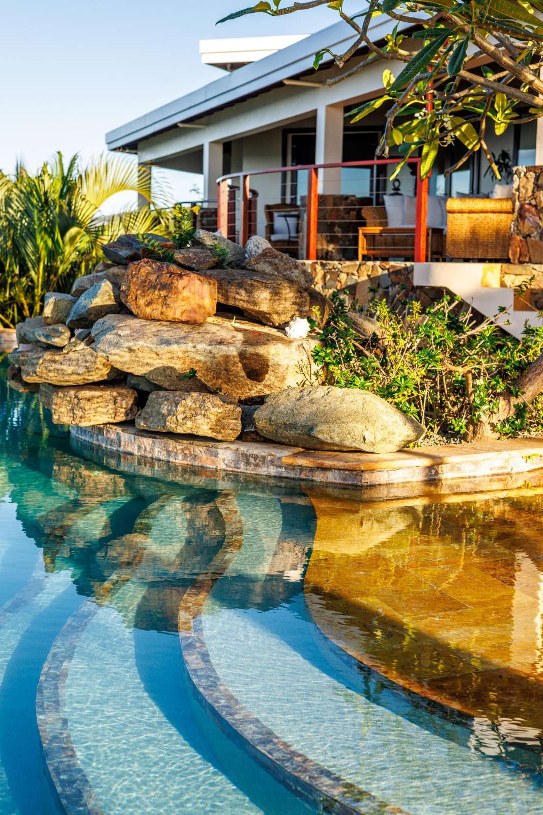Tranquil poolside retreat with cascading waterfall and lush greenery