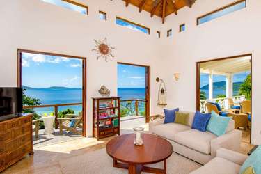 Sunlit living room with panoramic ocean views and cozy seating.