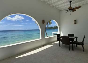 Oceanfront patio with stunning arched views and cozy dining area