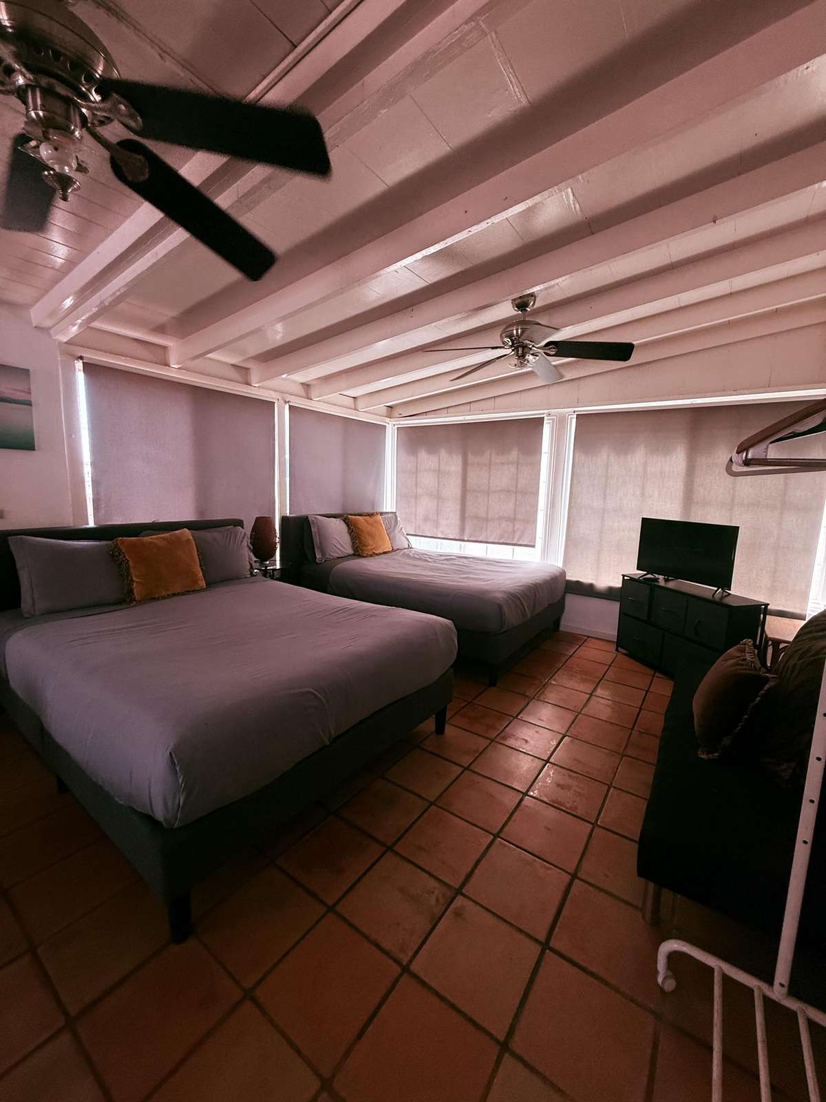 Bedroom Back upstairs Two queen beds with terracotta tile floors beneath exposed white beams and ceiling fans and air conditioner.