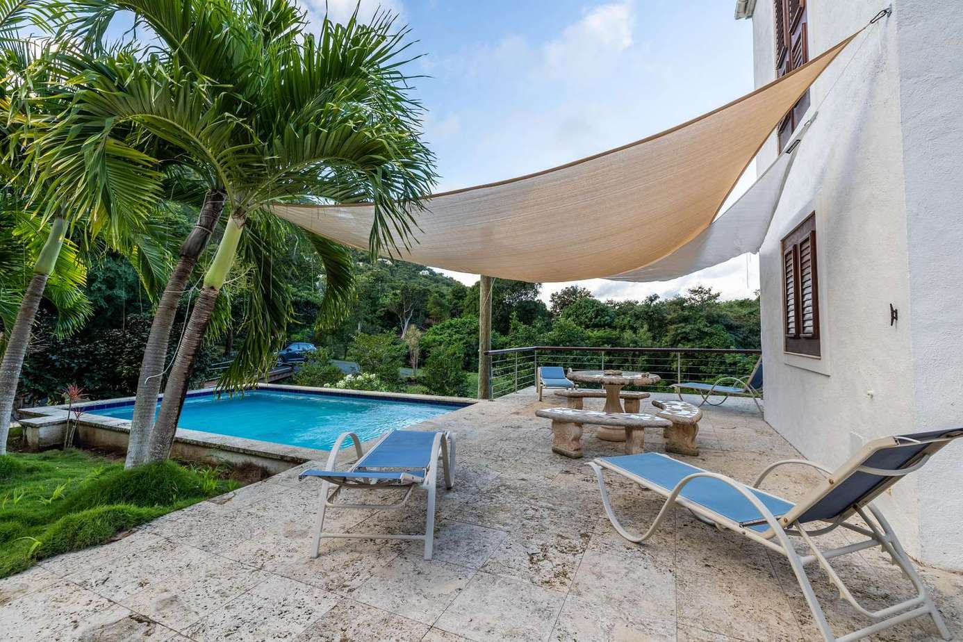 Relax by the pool under shaded tropical palms on the patio