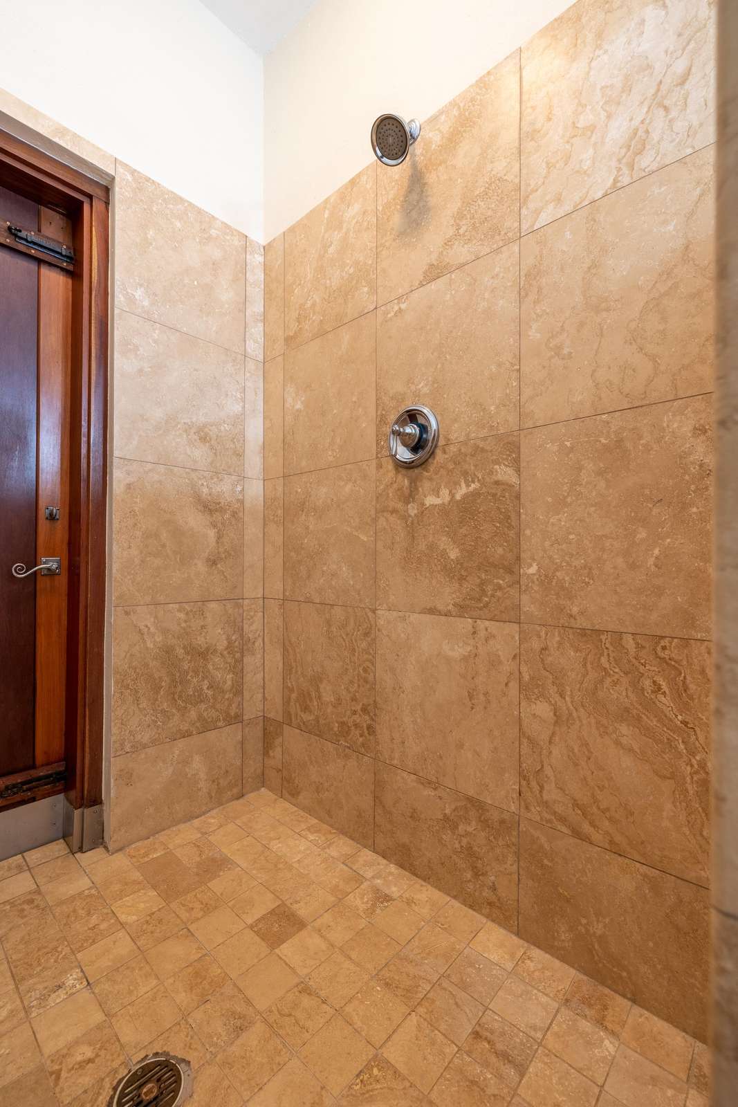 Spacious walk-in shower with warm stone tile retreat