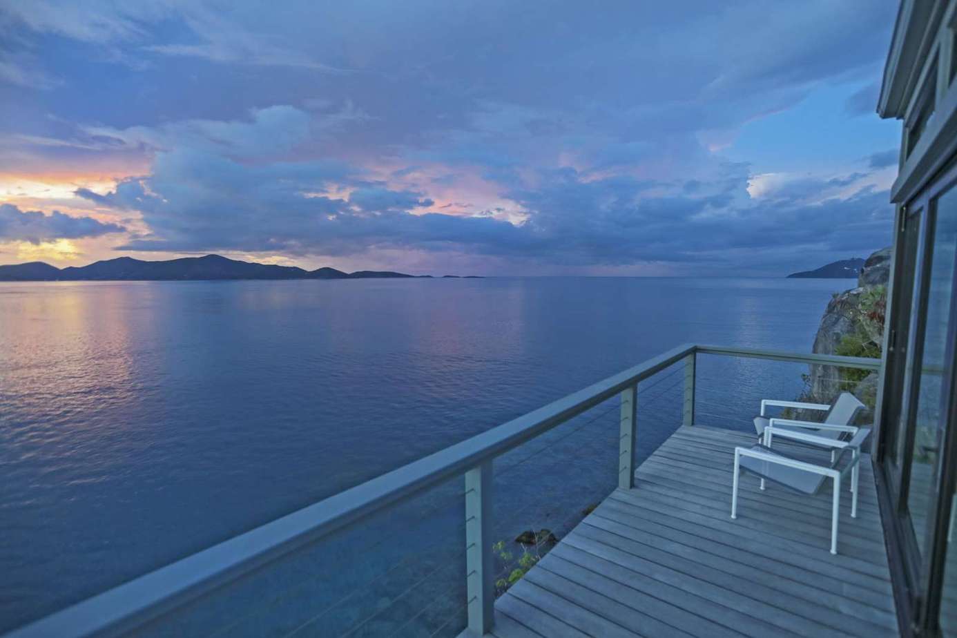Oceanfront balcony with stunning sunset views and cozy seating