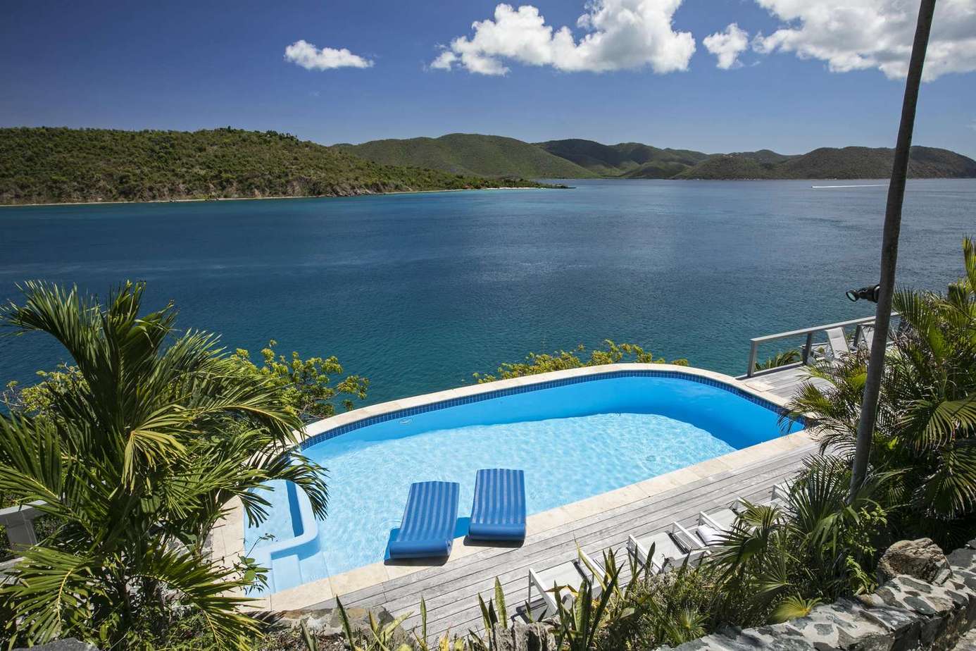 Infinity pool overlooking stunning ocean views and lush hills