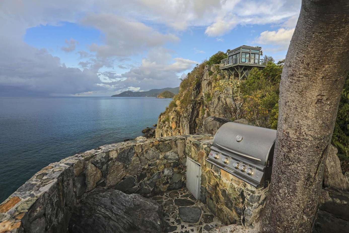 Secluded cliffside patio with panoramic ocean views and grill