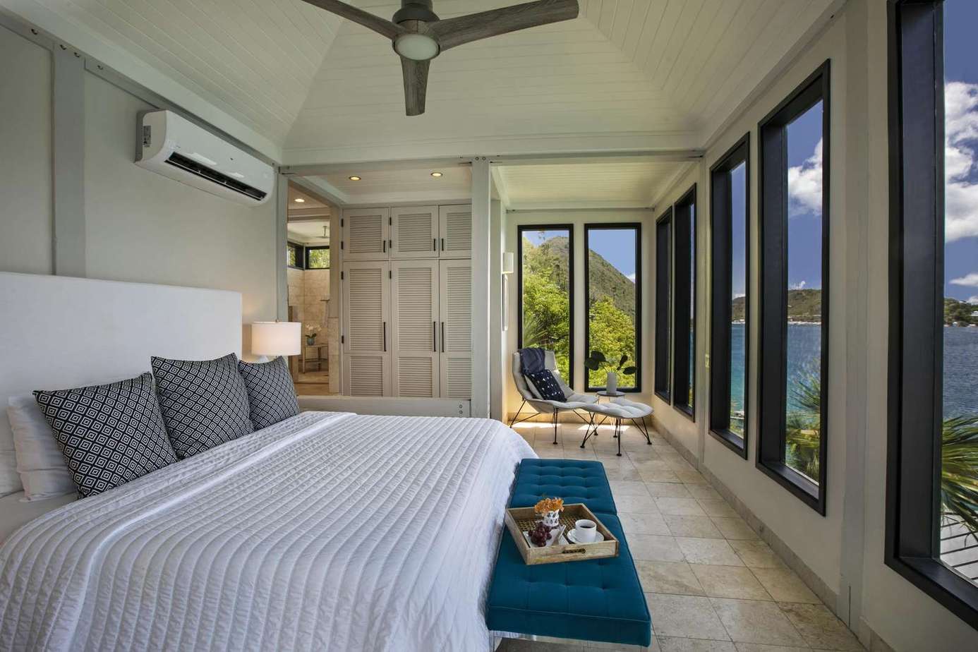 Sunlit bedroom with panoramic window views and cozy seating