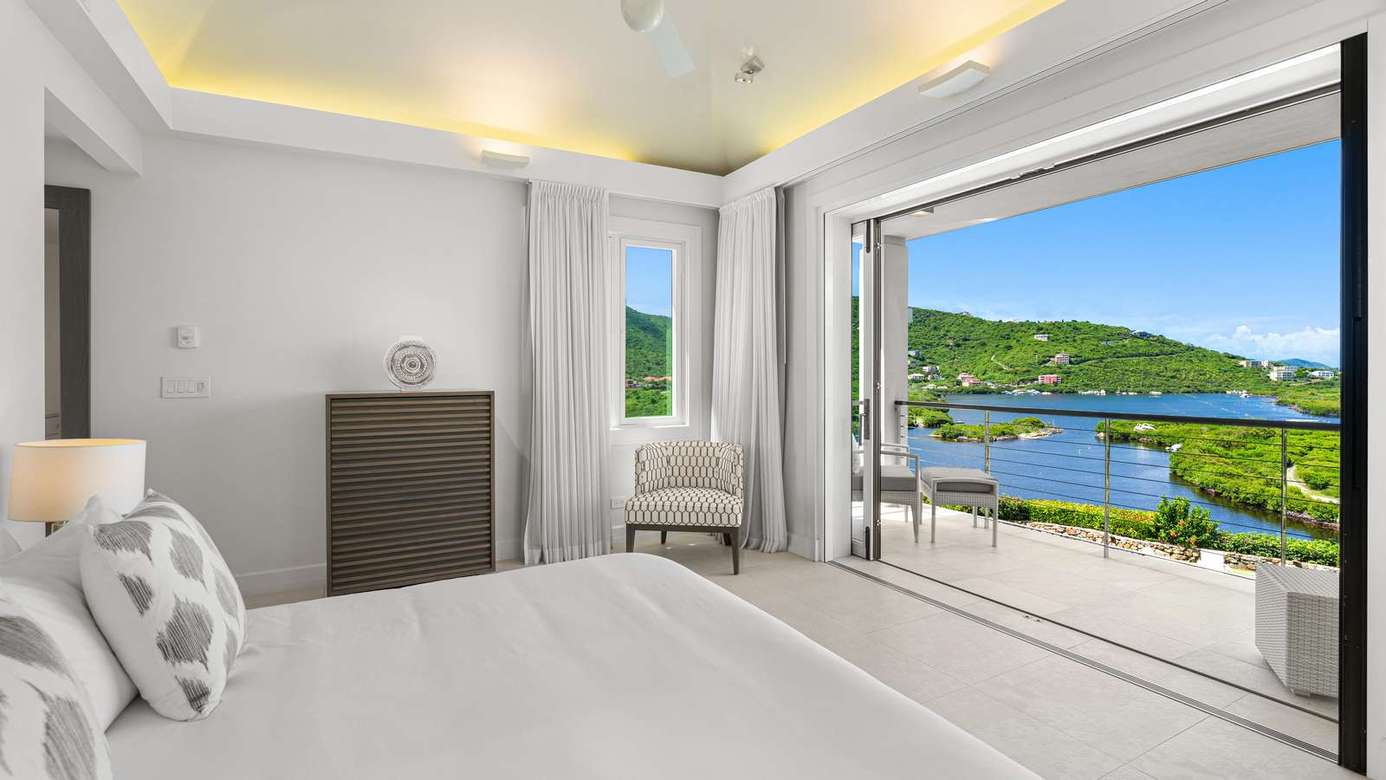 Serene bedroom with panoramic waterfront views and natural light