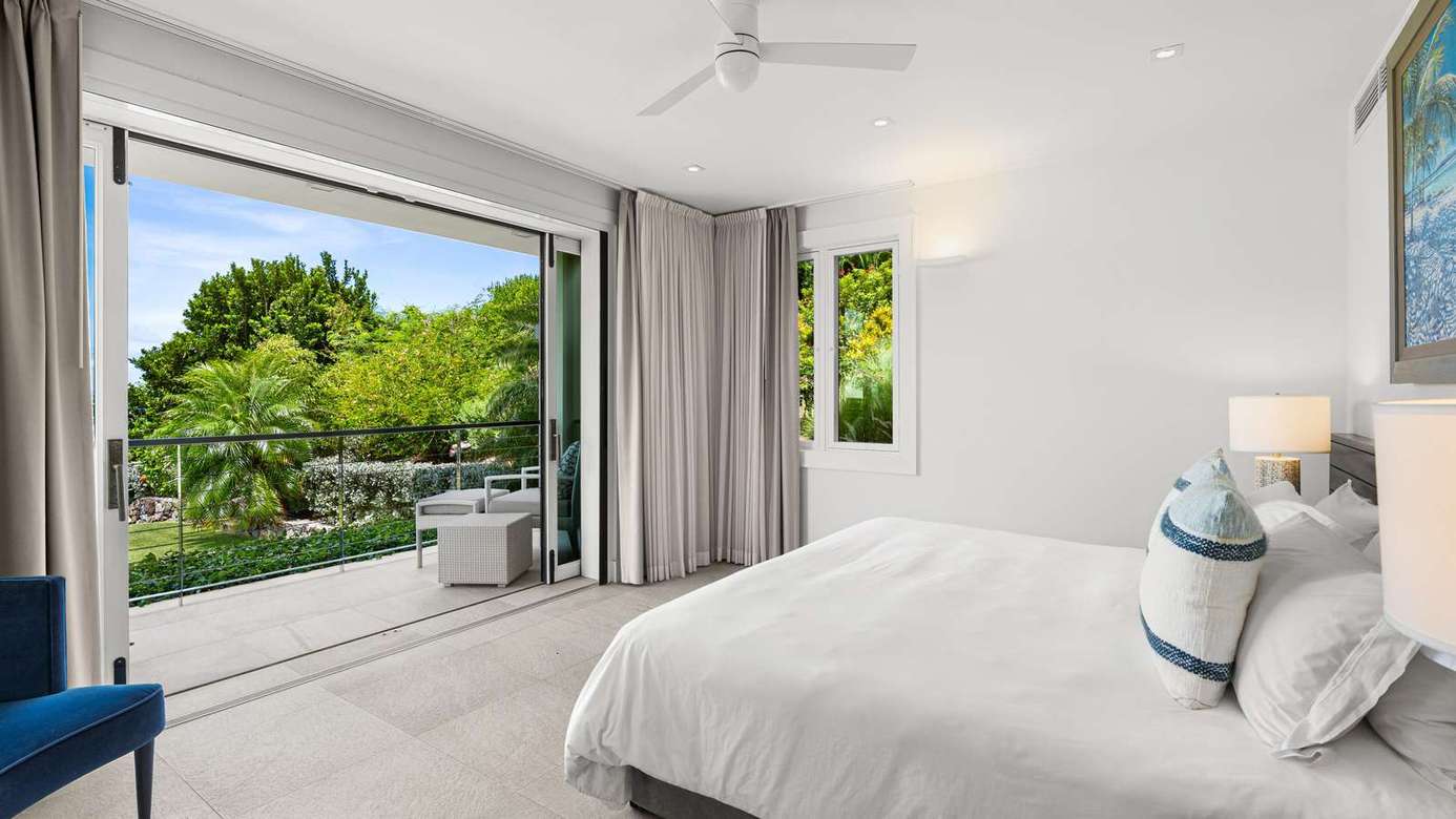 Bright bedroom with seamless indoor-outdoor flow and lush views