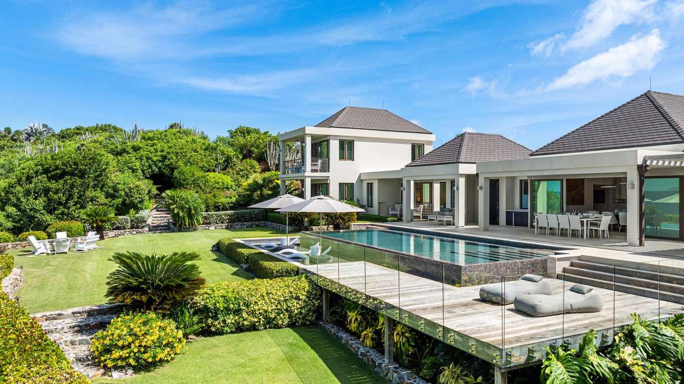 Expansive outdoor pool and lounge area with lush garden views