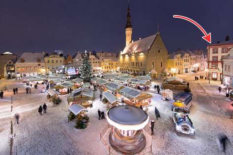 View of the apartment’s corner rooftop overlooking a bustling, snow-covered Christmas market in Tallinn’s Old Town square.