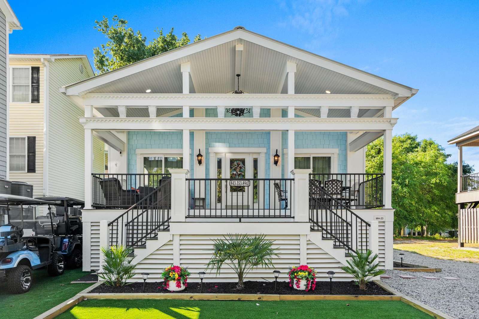 Front porch with light blue shingle siding, white columns, black metal railing, and outdoor seating areas. - property