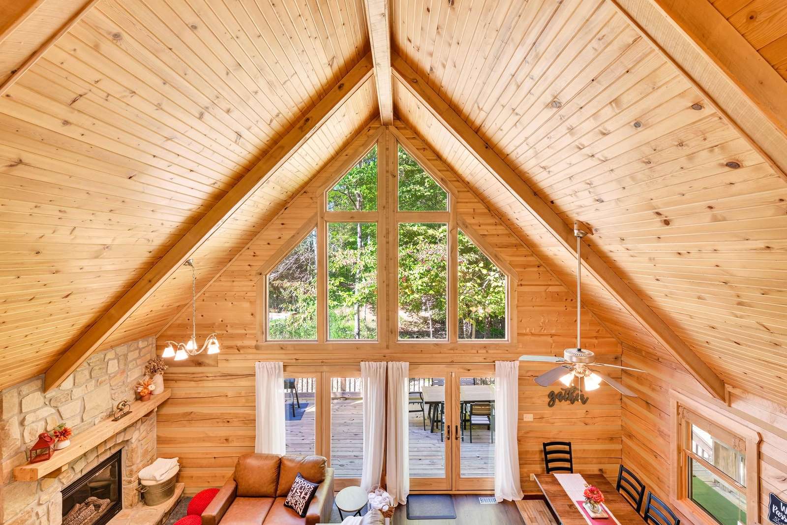 Sunlit loft living room with vaulted ceilings and forest views