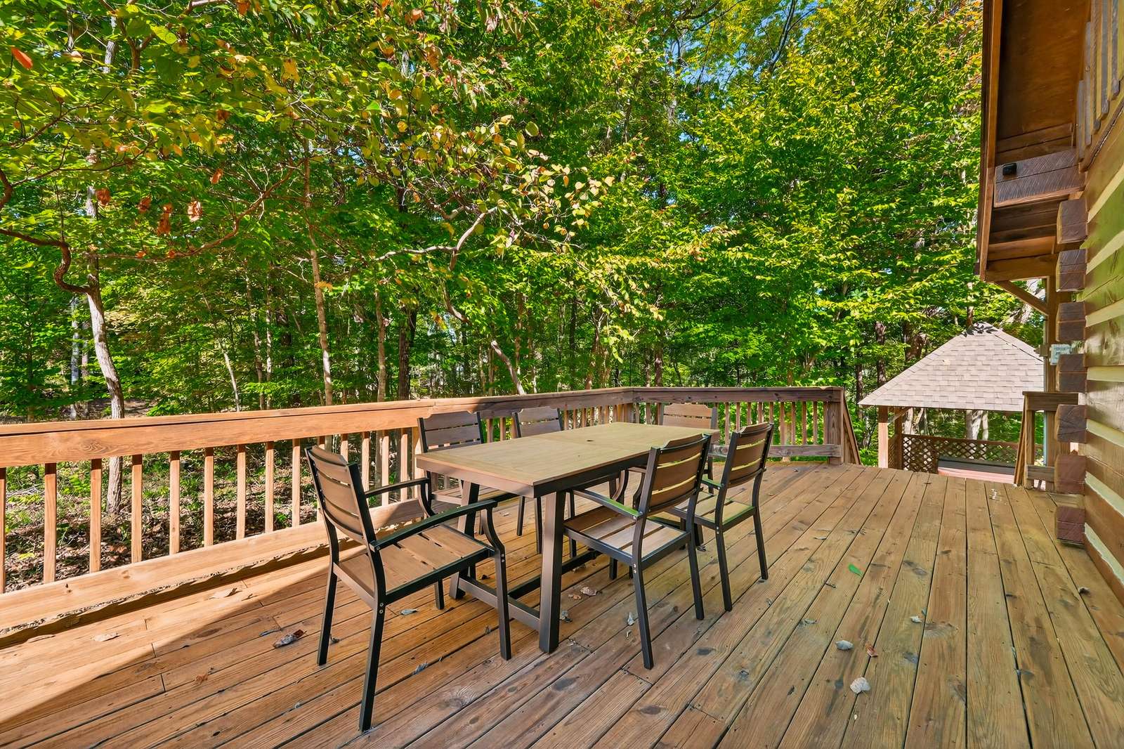 Spacious outdoor deck with dining area surrounded by lush trees