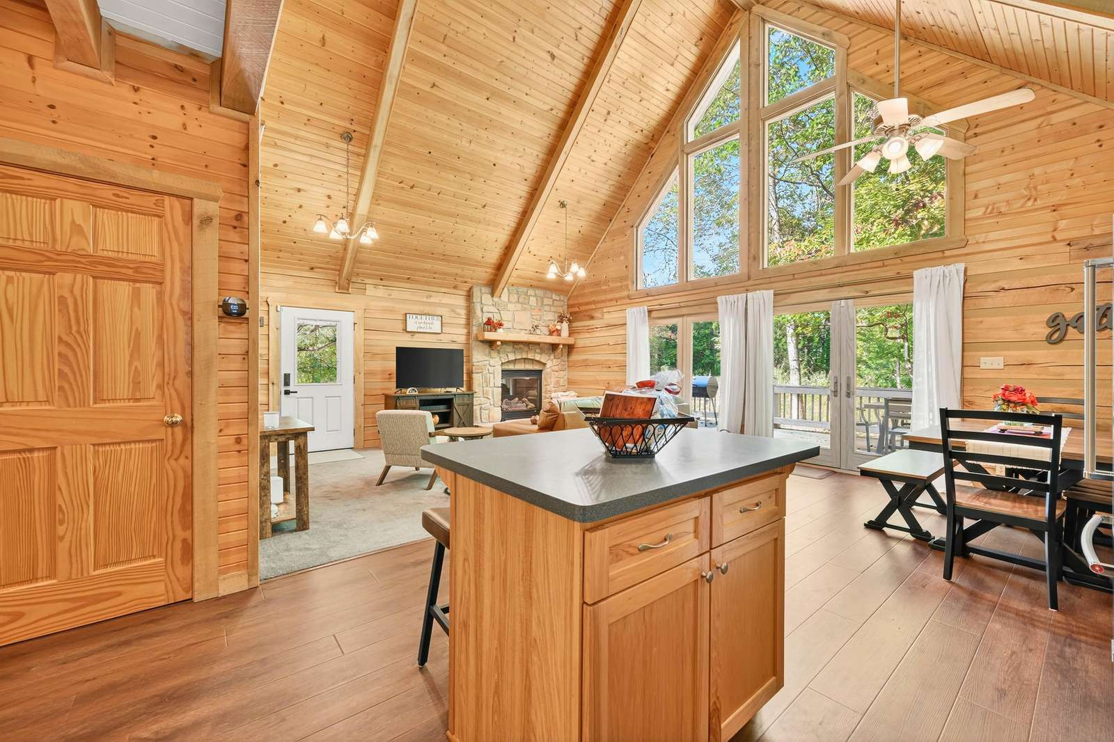 Sunlit kitchen and dining area with vaulted ceilings and forest views