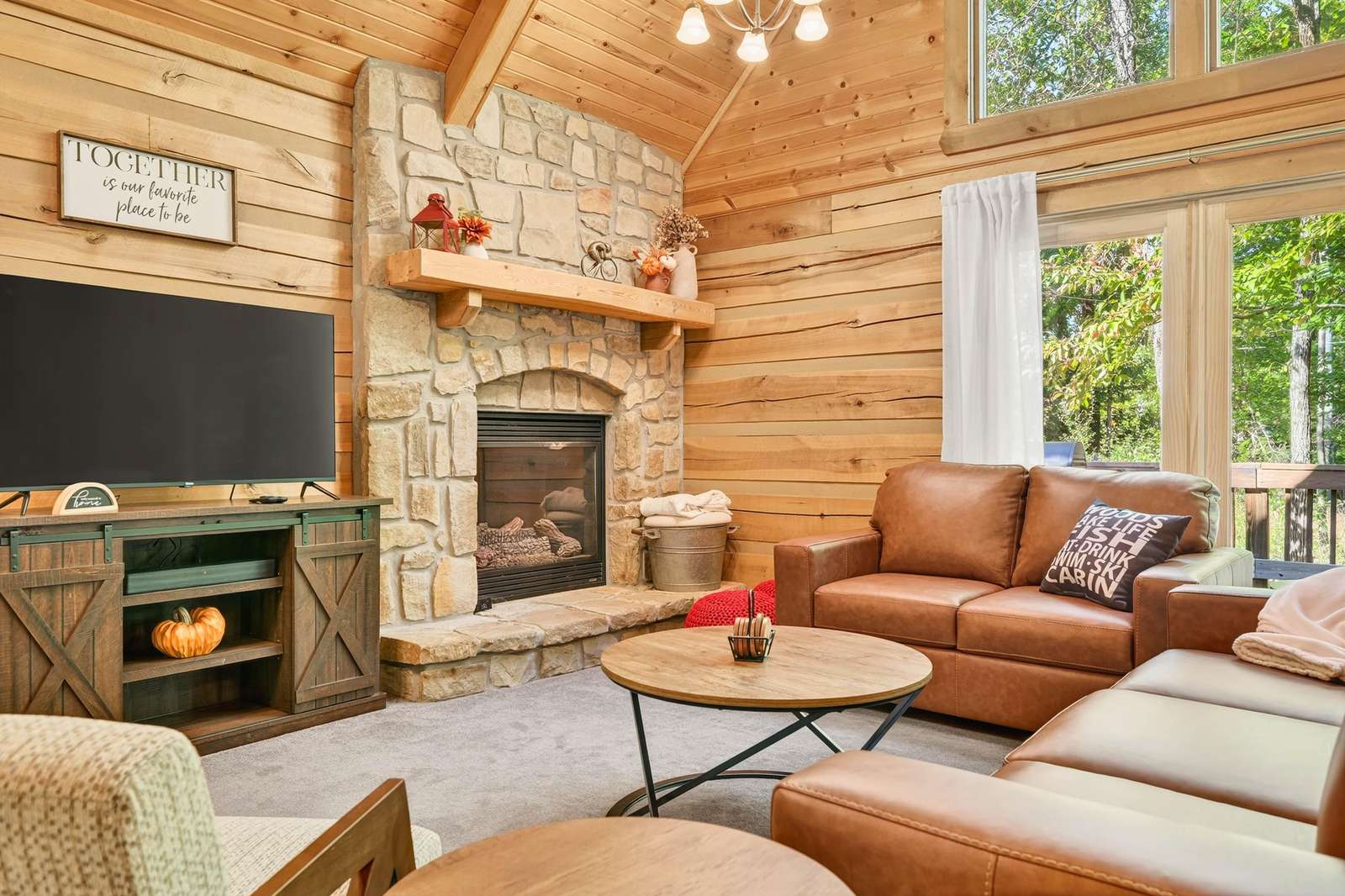 Cozy living room with stone fireplace and forest views