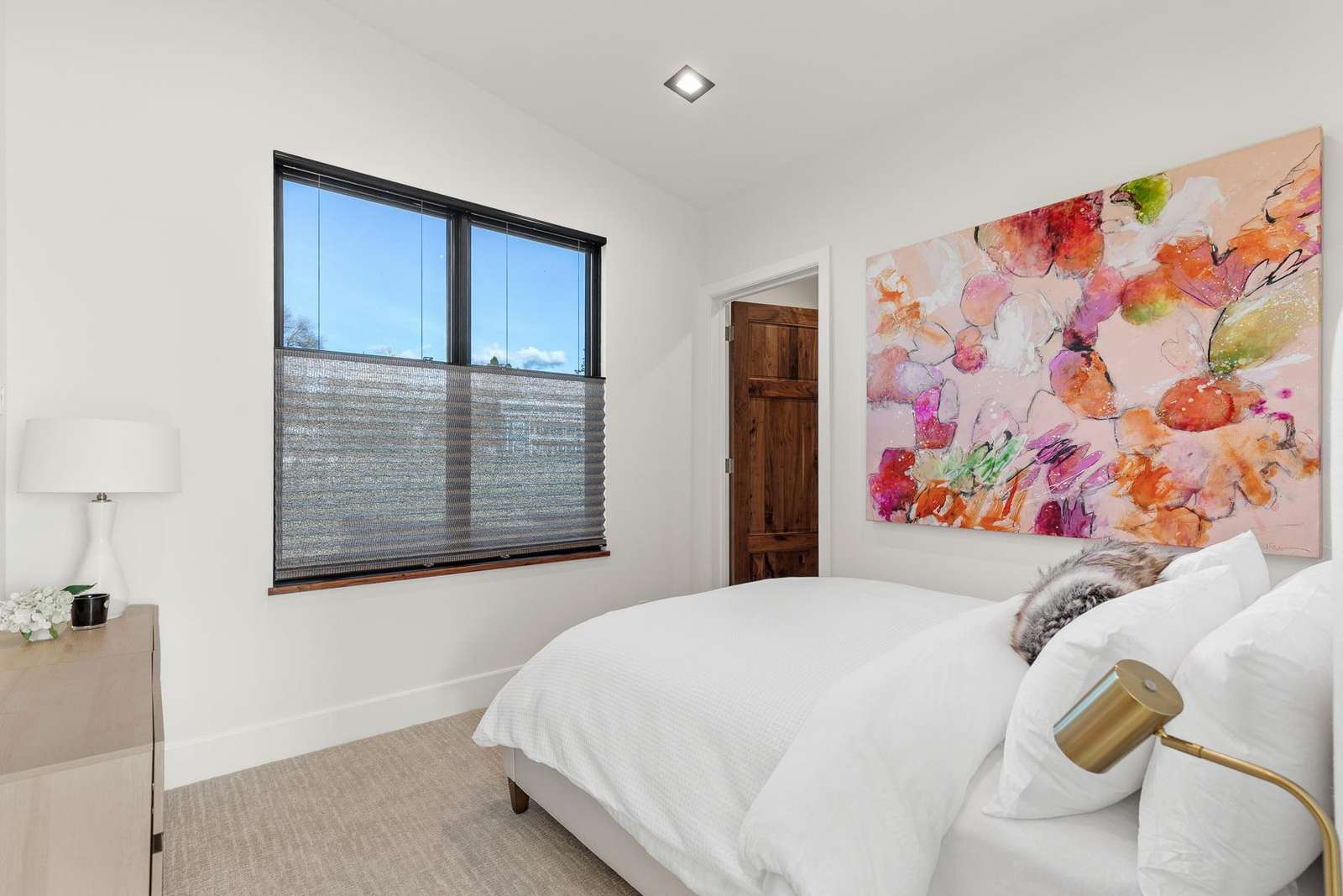 Bright and cozy bedroom with vibrant floral artwork and natural light