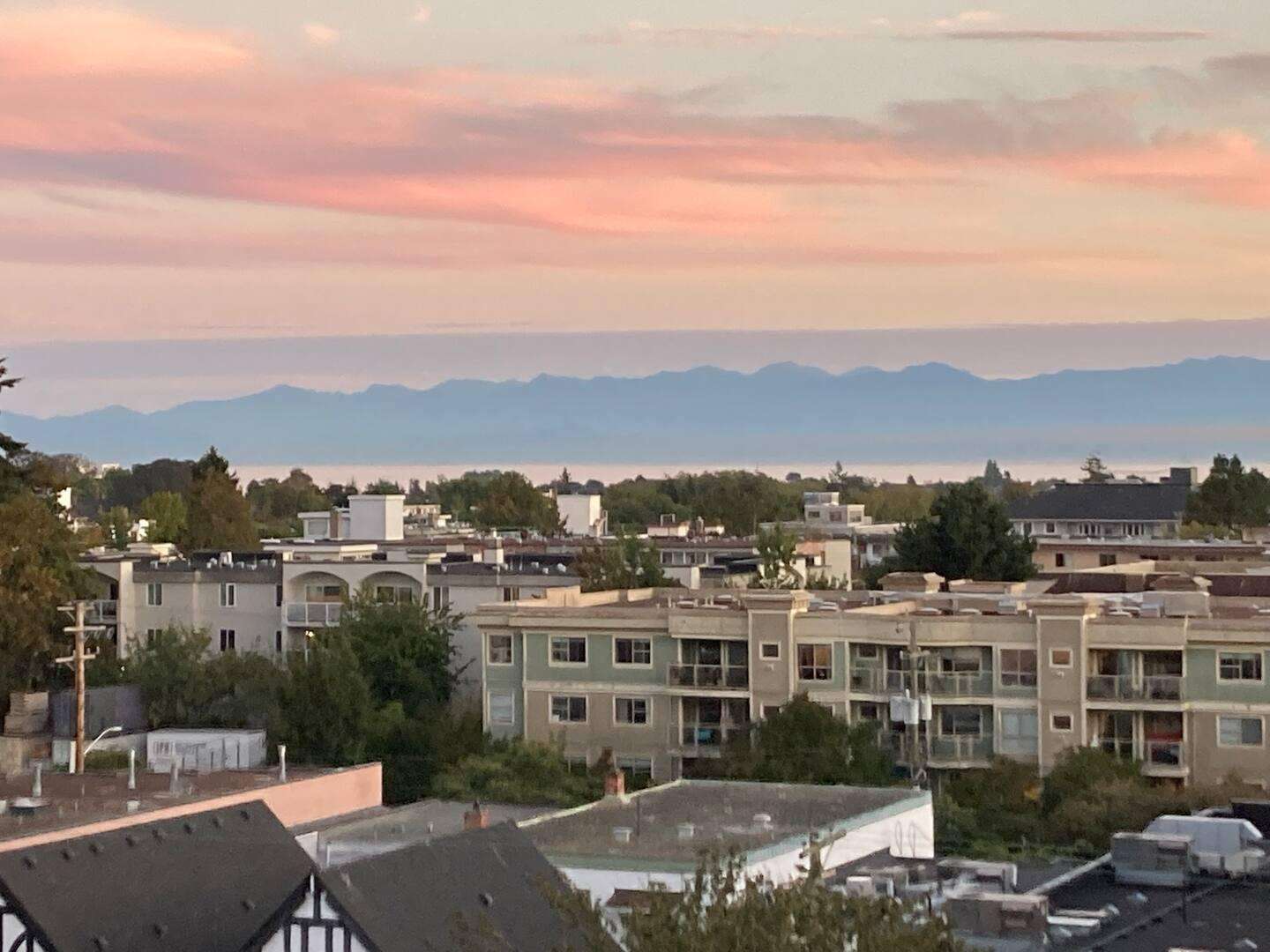 Sunset views over cozy neighborhood rooftops and distant mountains - property