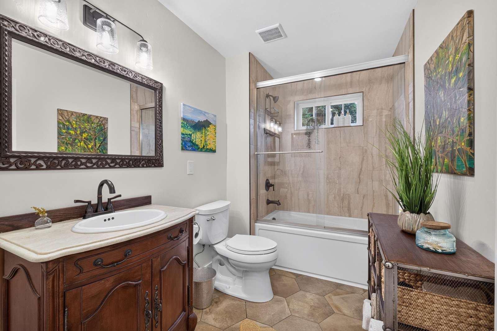 Bathroom featuring a wood vanity with marble countertop, hex tile floor, and a tub-shower with glass doors and beige tile surround.