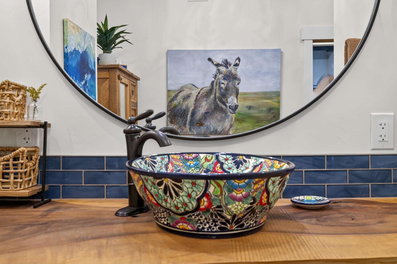 Bathroom vanity features a colorful hand-painted ceramic vessel sink atop a natural wood countertop.