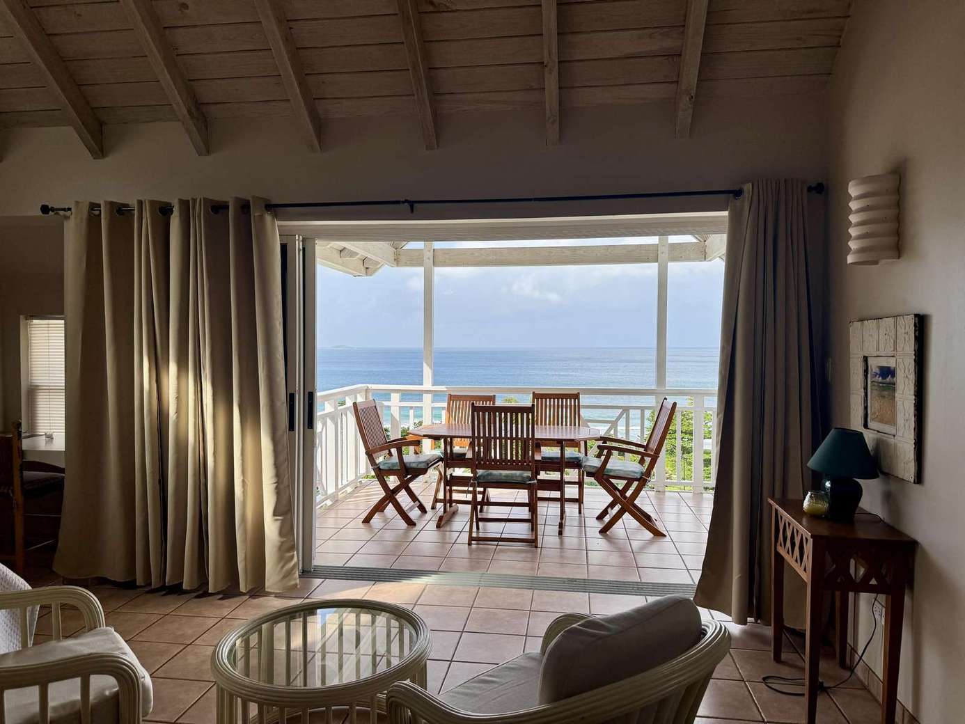 Sunlit living room opening to oceanfront dining terrace