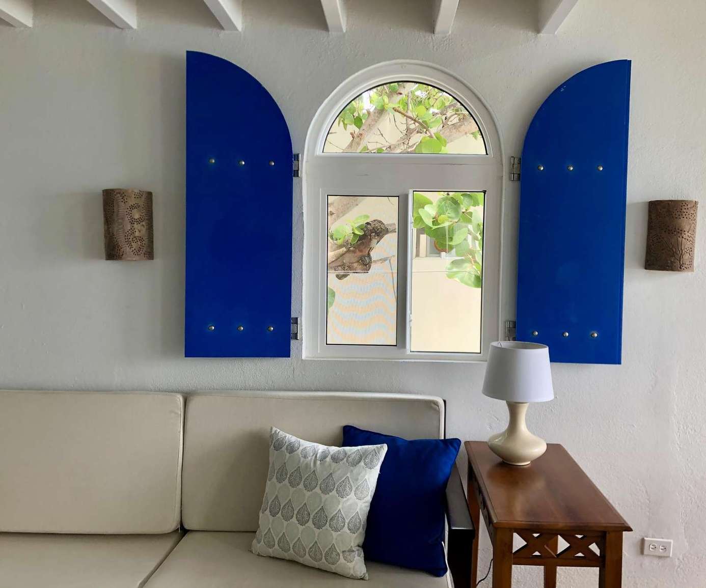 Cozy living room with charming arched window and vibrant shutters