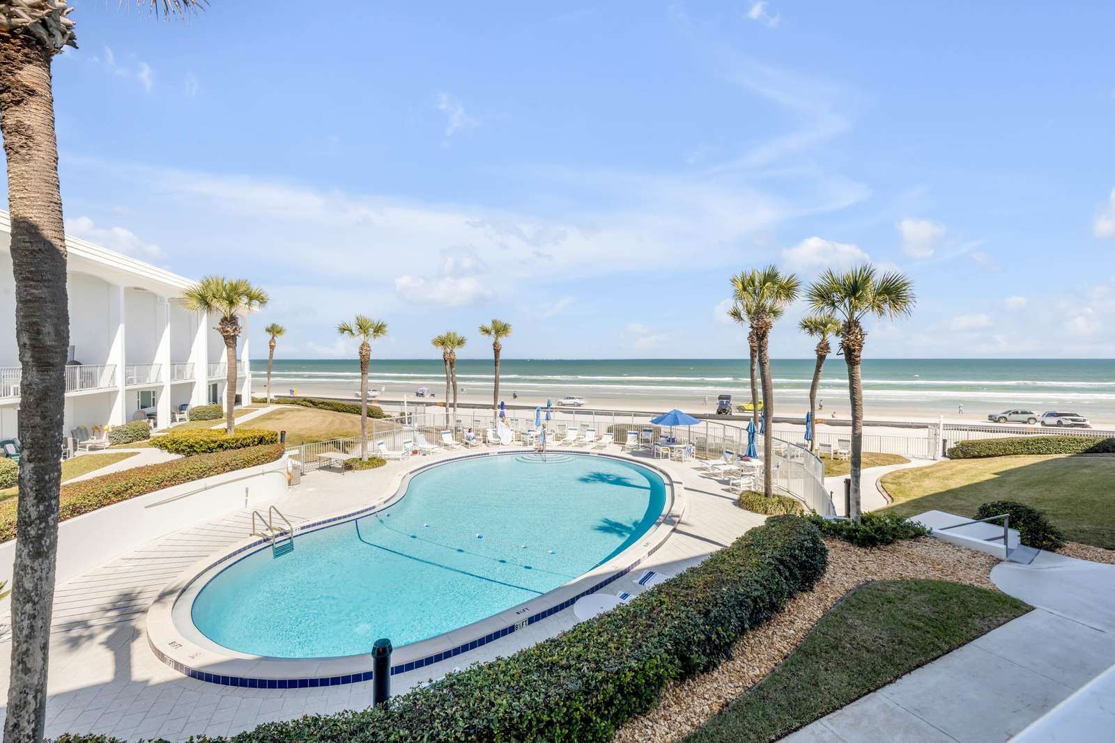 Oceanfront pool area with stunning beach views and palm trees - property