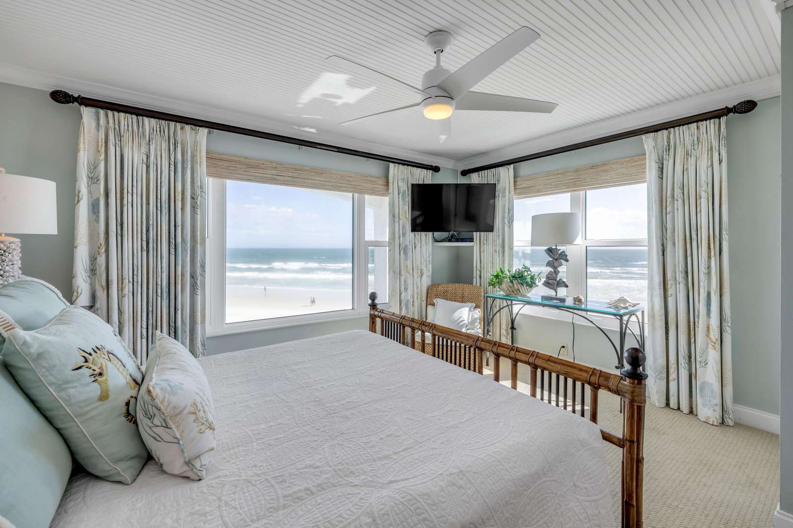 Oceanfront bedroom with panoramic beach views and serene decor - property