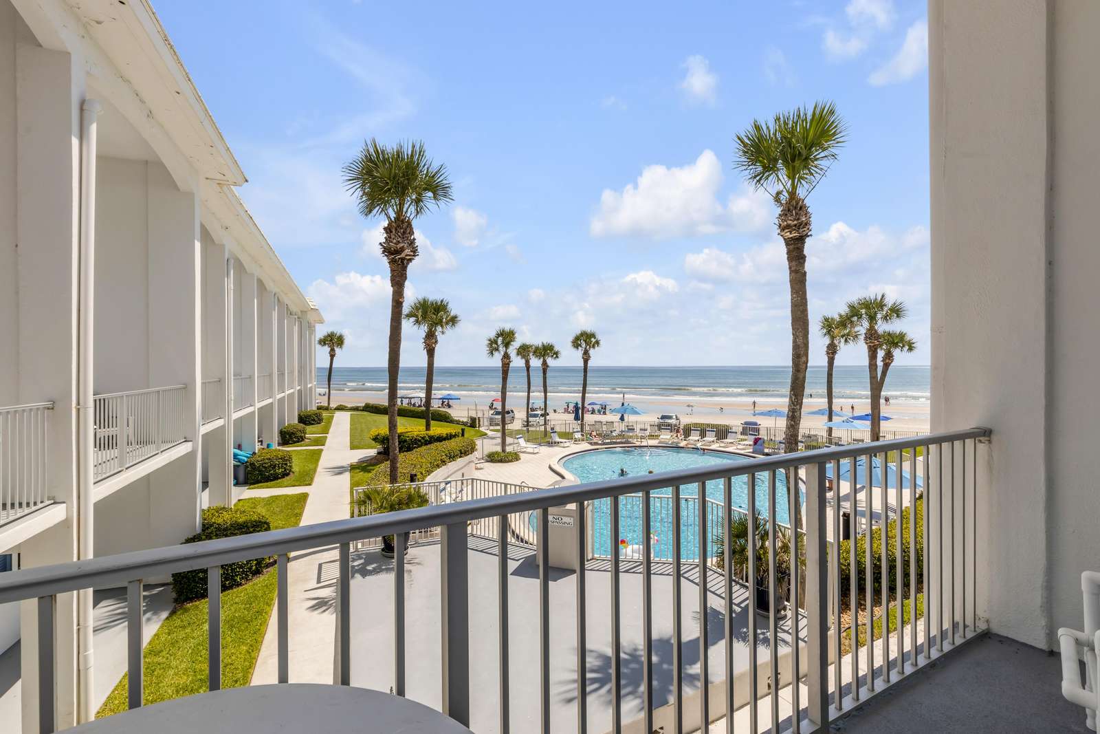 Oceanfront balcony with stunning pool and palm tree views - property