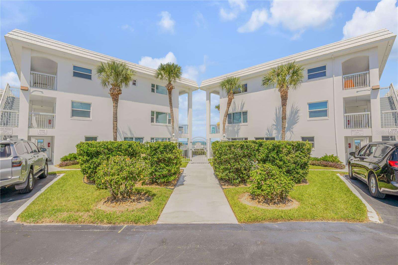 Bright, airy exterior with lush landscaping and palm trees - property