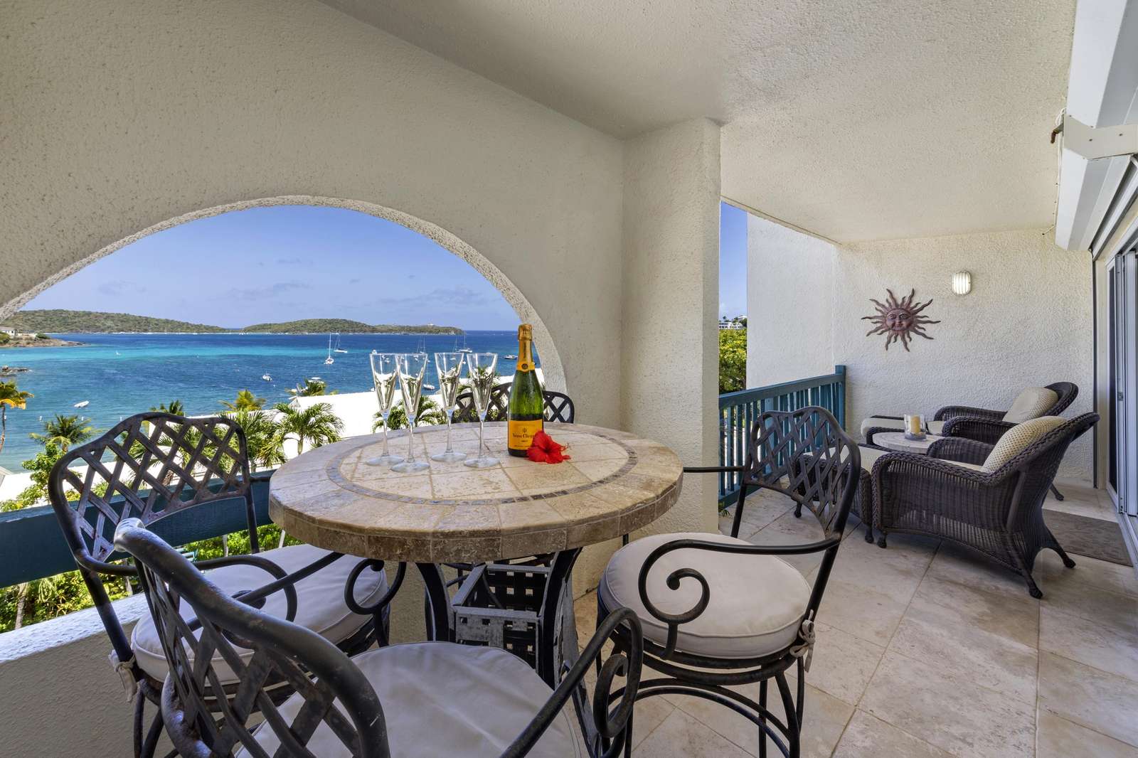 High-top dining table with wrought iron chairs and cushioned wicker lounge seating on covered balcony with incredible view! - property