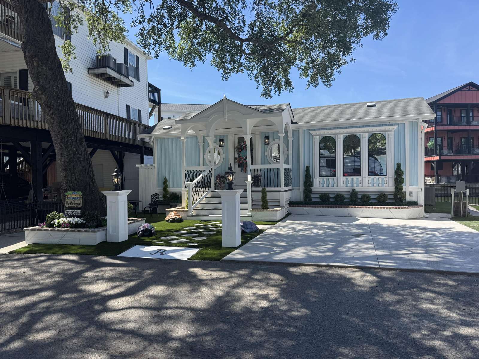 Front yard with artificial grass, stepping stones, decorative turtle sculptures, and white porch with arches and lanterns. - property