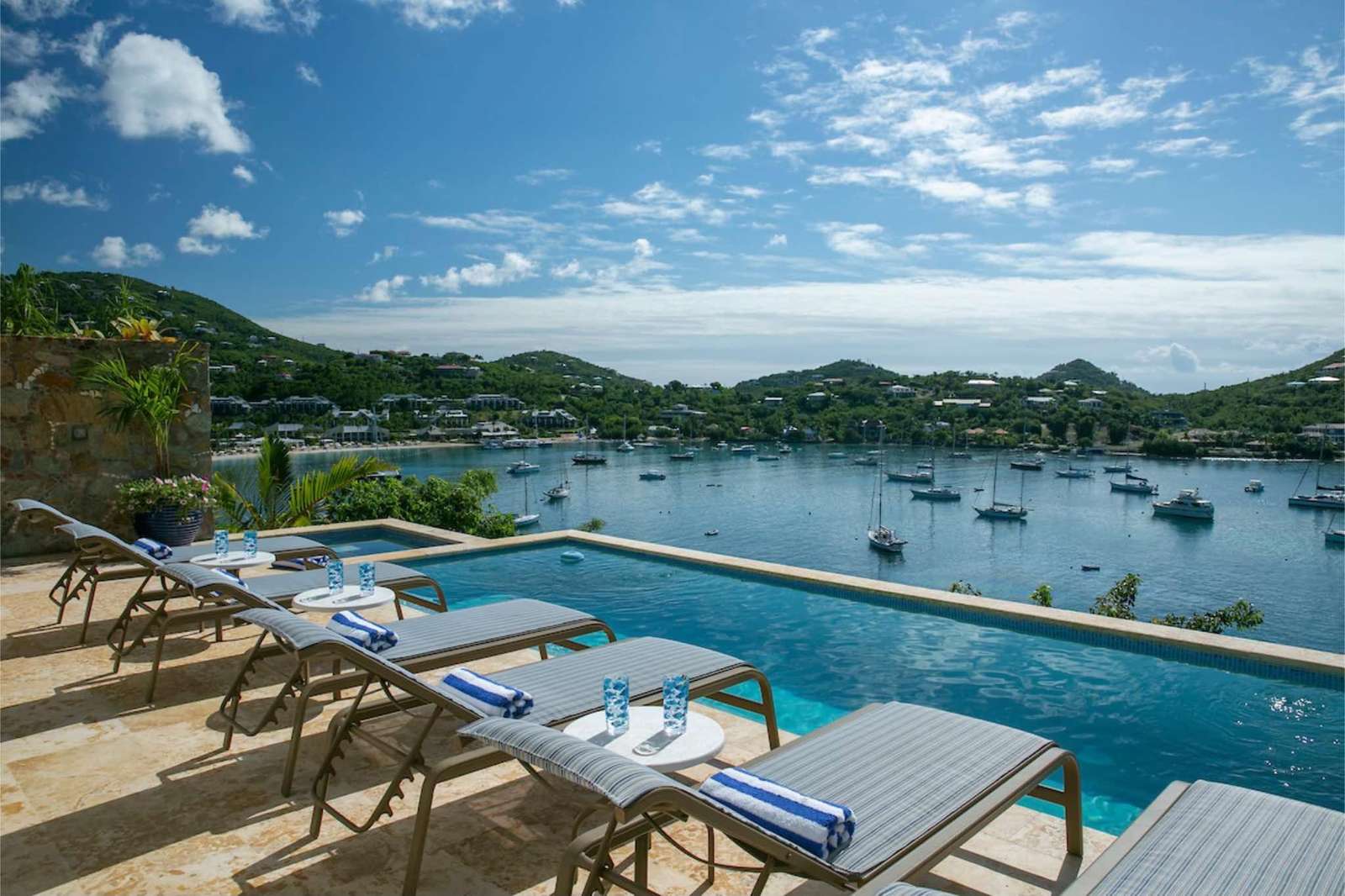 Infinity pool and sun loungers overlooking serene bay views - property