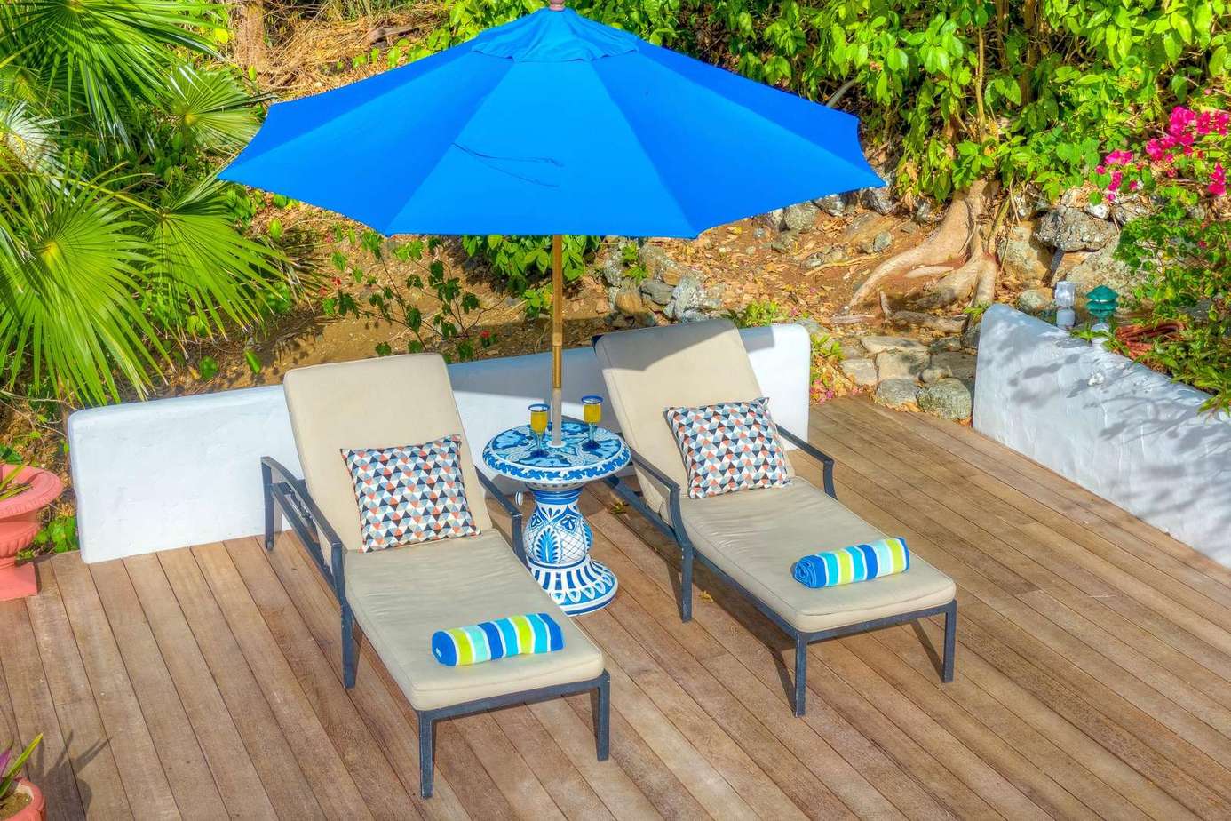 Sunny deck with loungers and vibrant blue umbrella for relaxing outdoors