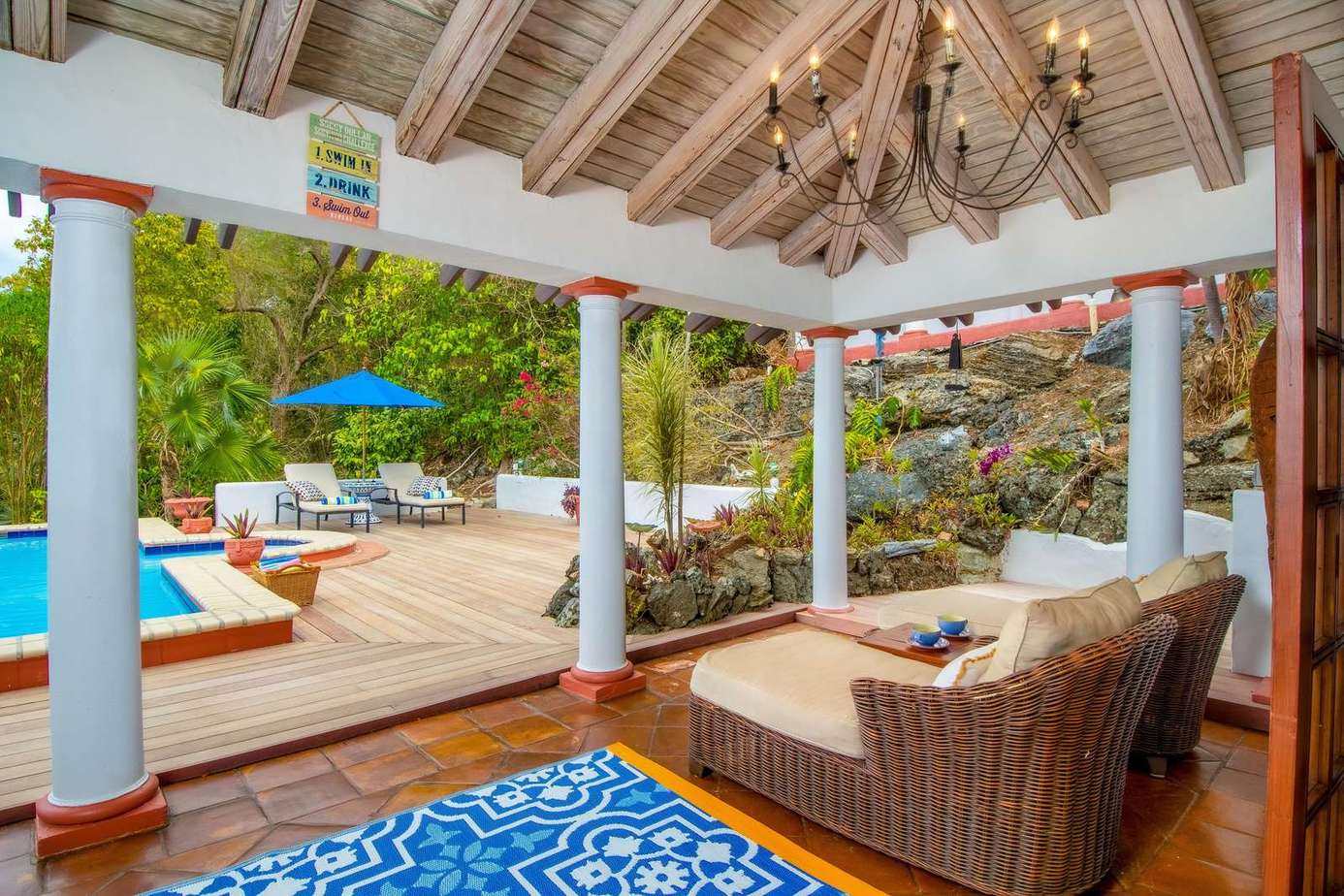 Covered patio with cozy seating overlooking pool and lush garden