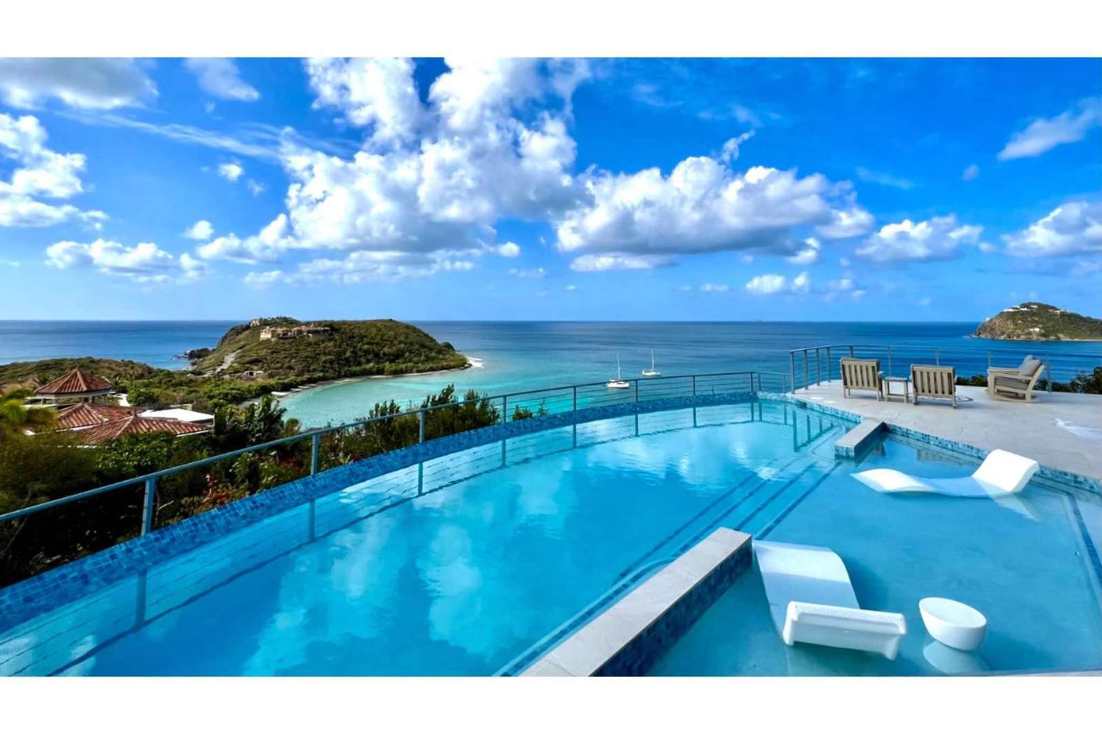 Infinity pool with panoramic ocean views and lounge seating - property