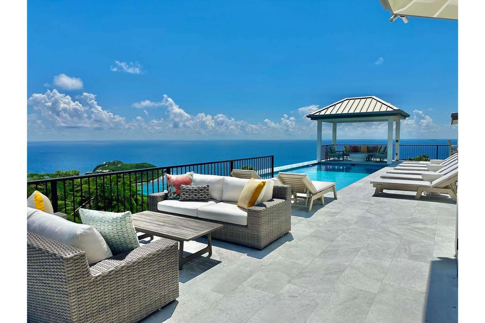 Sun-soaked patio with infinity pool and ocean views - property