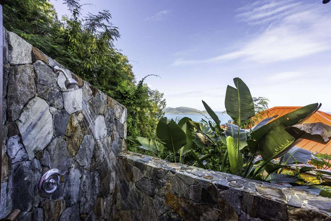 Secluded outdoor stone shower surrounded by lush greenery