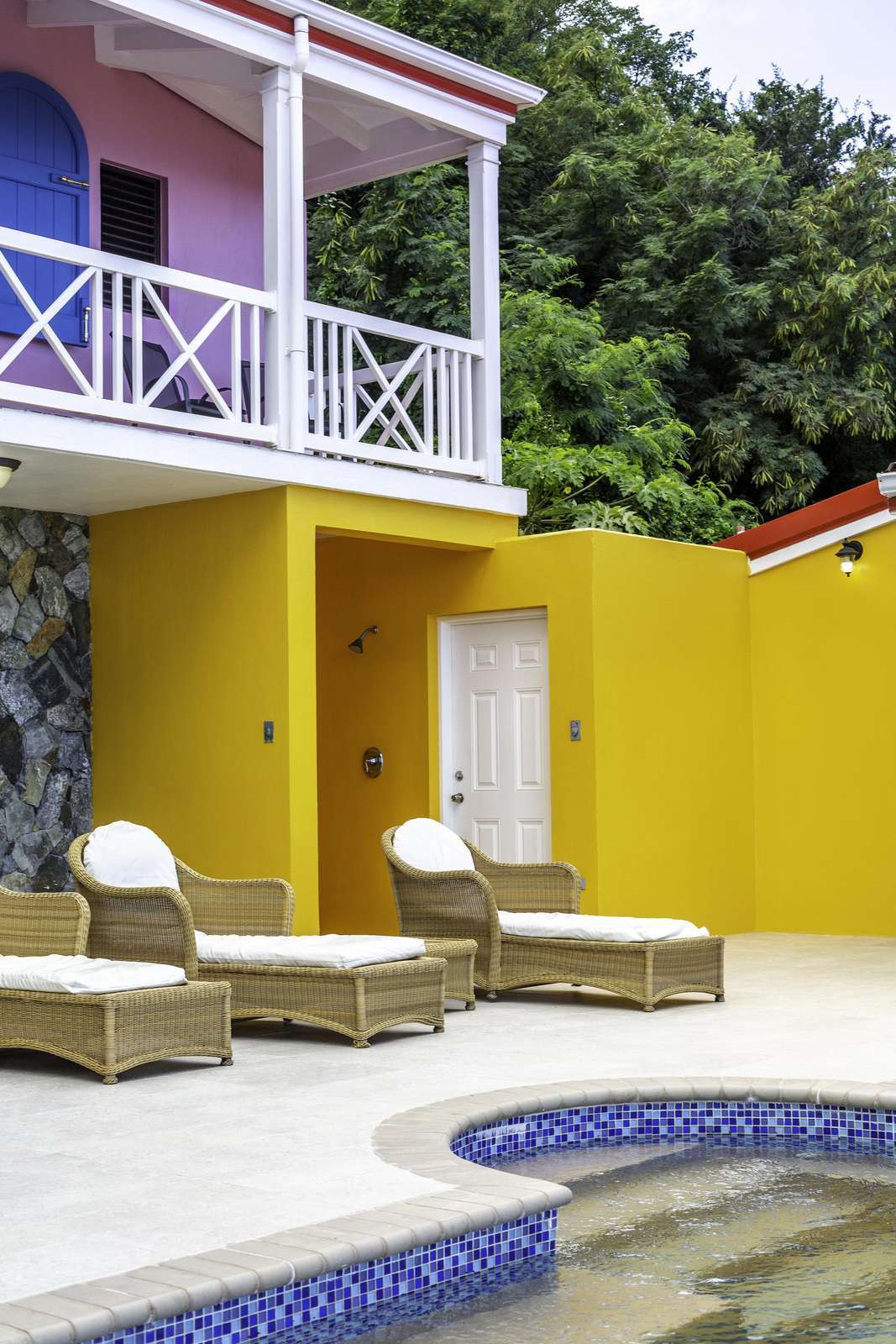 Sunny poolside patio with vibrant walls and cozy loungers