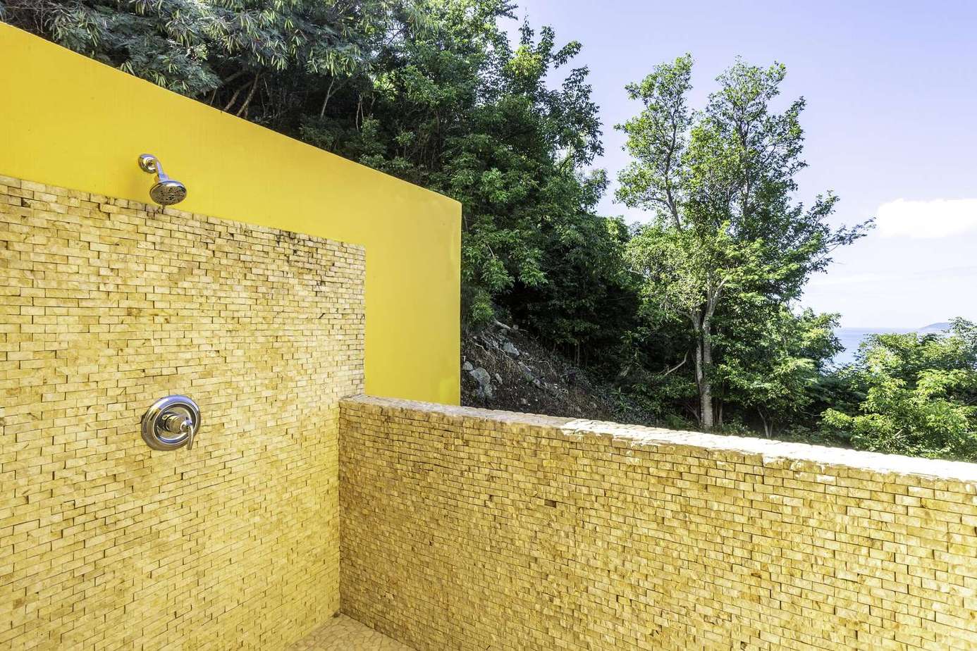 Sunny outdoor patio with vibrant yellow walls and lush views