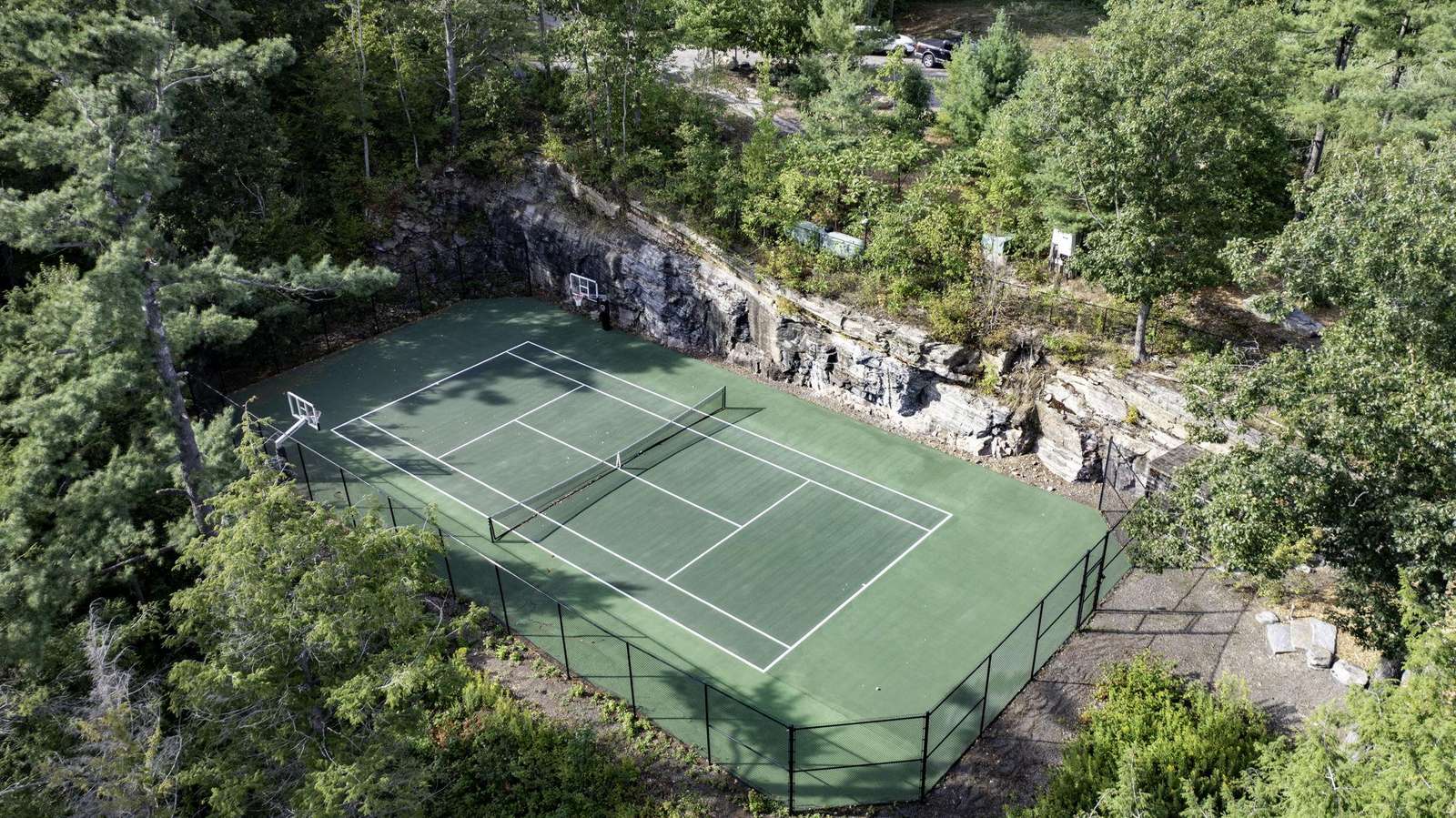 Tennis court nestled beside natural rock waterfalls and trees