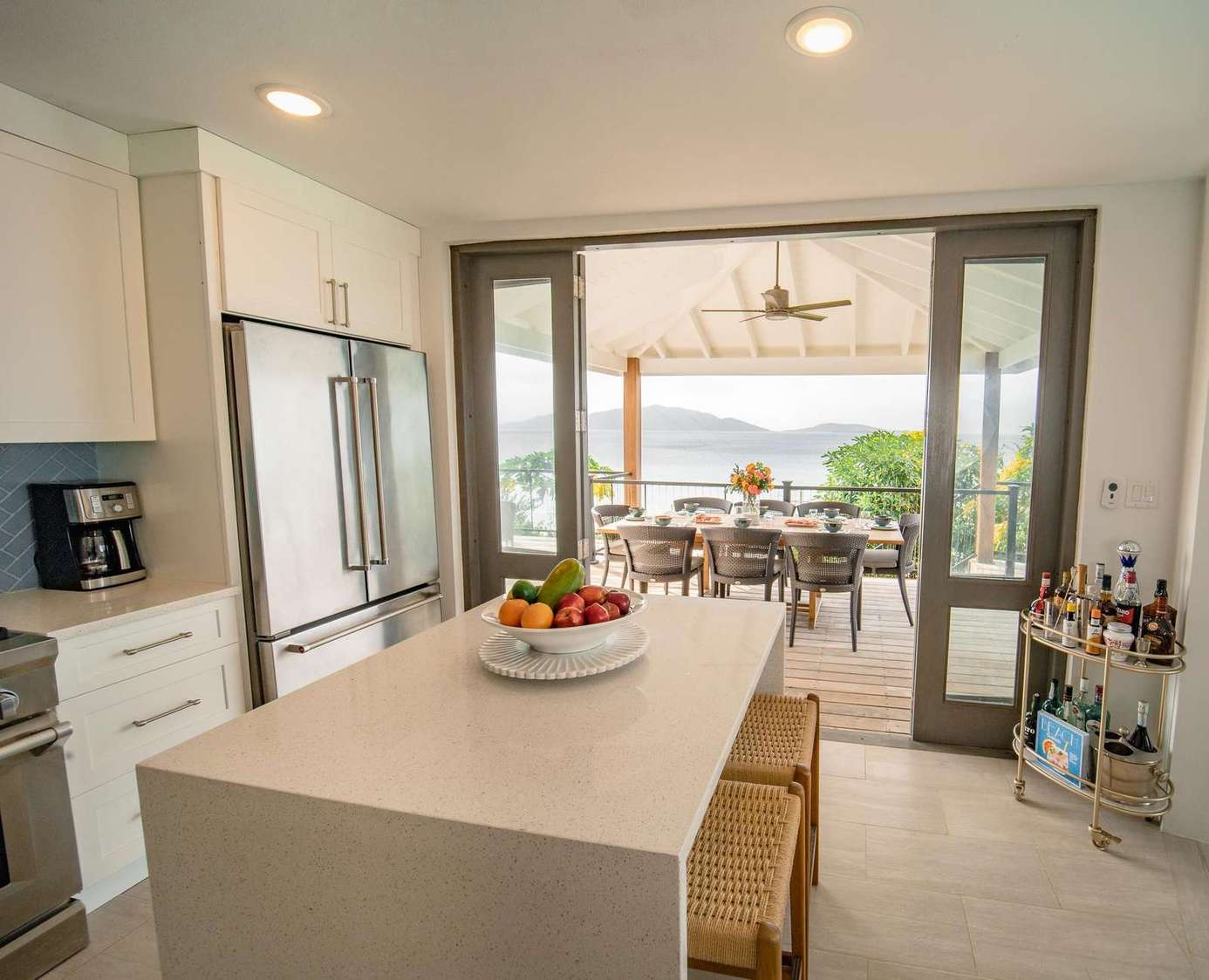 Bright modern kitchen with ocean view and outdoor dining area.