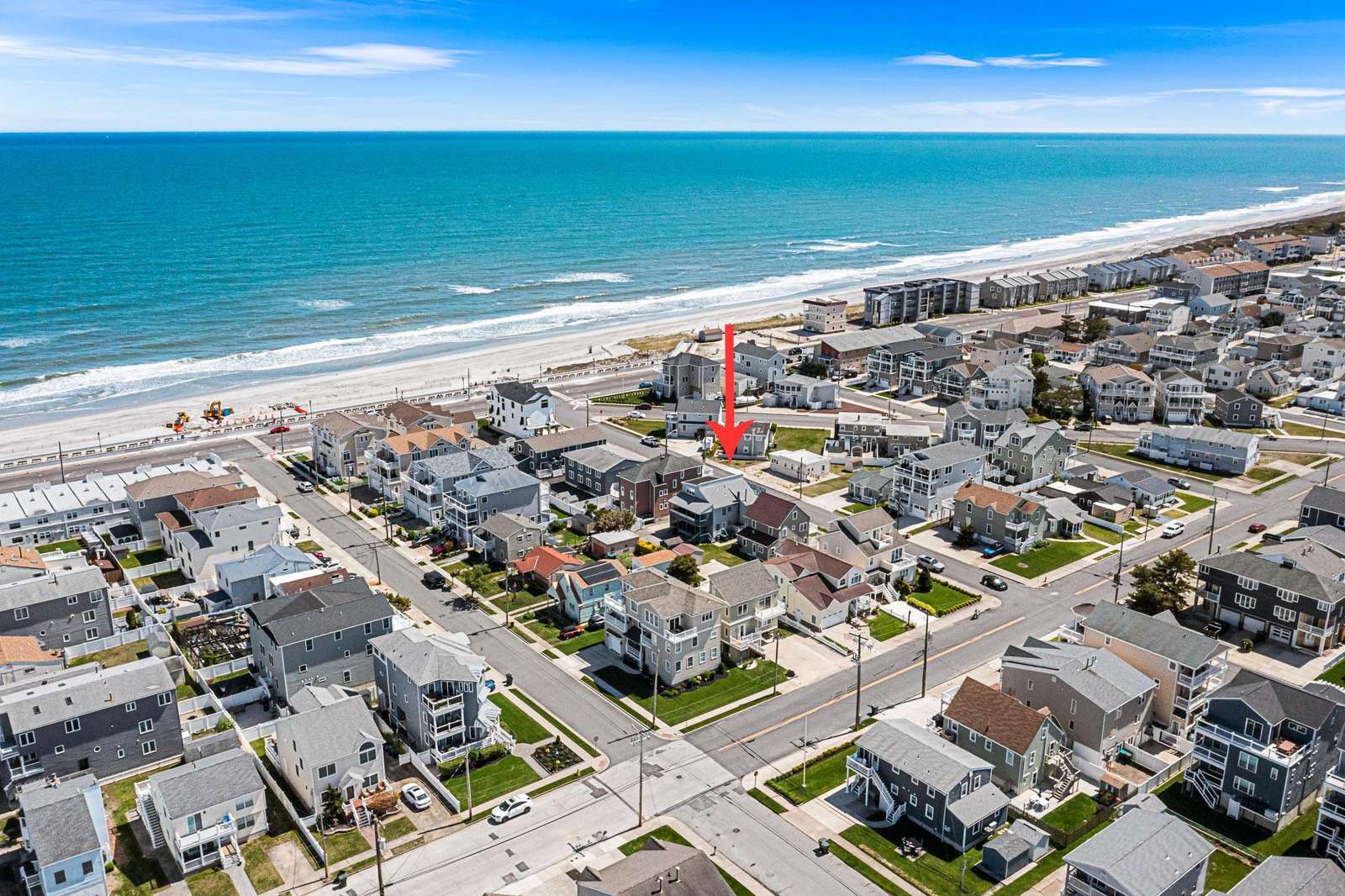 Aerial view shows the condo marked by a red arrow, close to the sandy beach and ocean horizon. - property