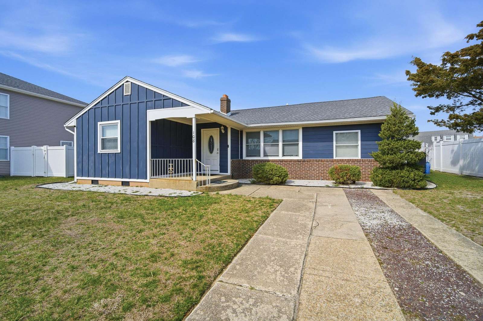 Blue siding and brick exterior frame the front porch and multiple windows of the single-story house. - property