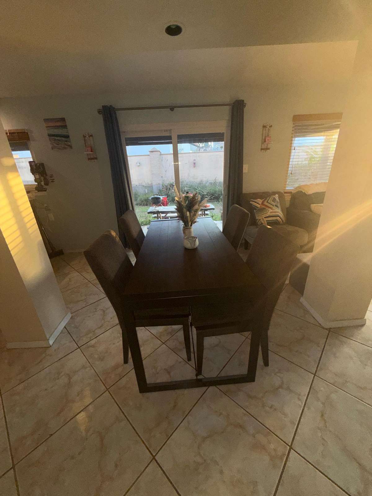 Dark wood dining table with six cushioned chairs on beige tile floor near sliding glass door. - property