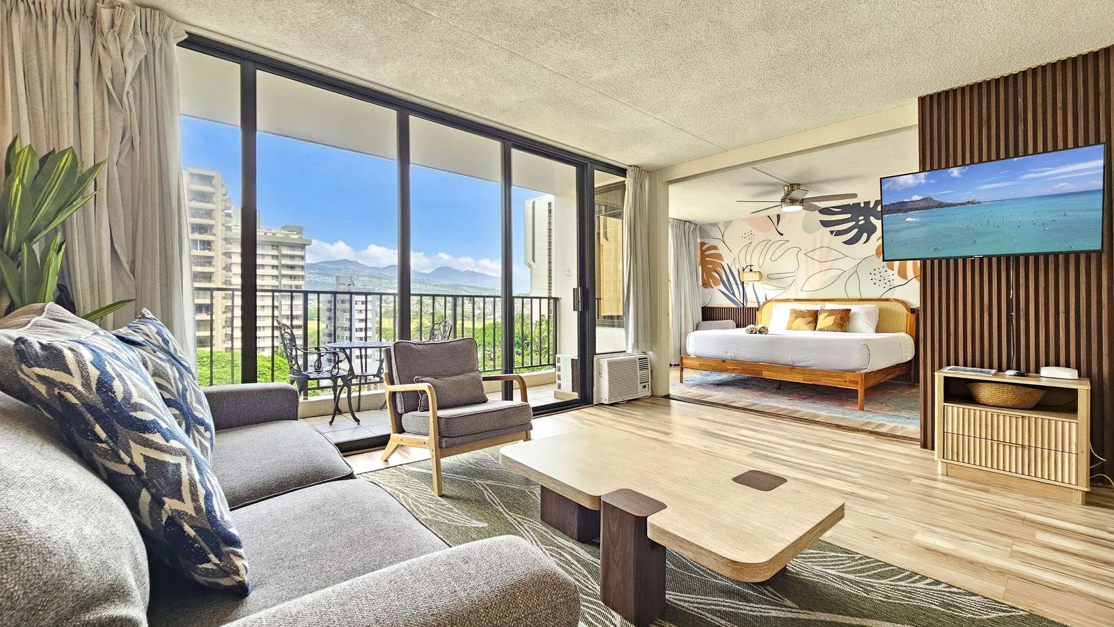 Sliding glass doors open from the living area to a balcony with wrought-iron table and city views. - property